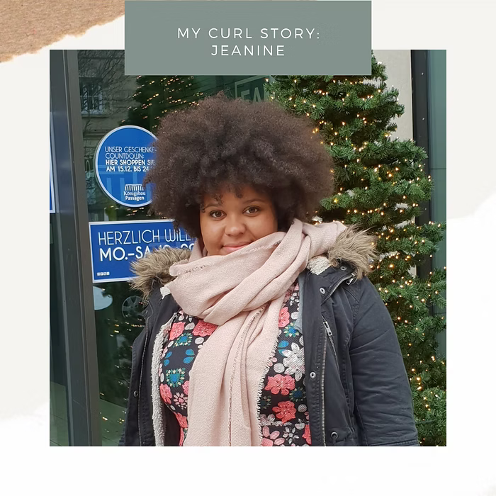 Frau mit großem Afro steht im Winter mit Schal und Jacke vor einem beleuchteten Weihnachtsbaum in der Stadt