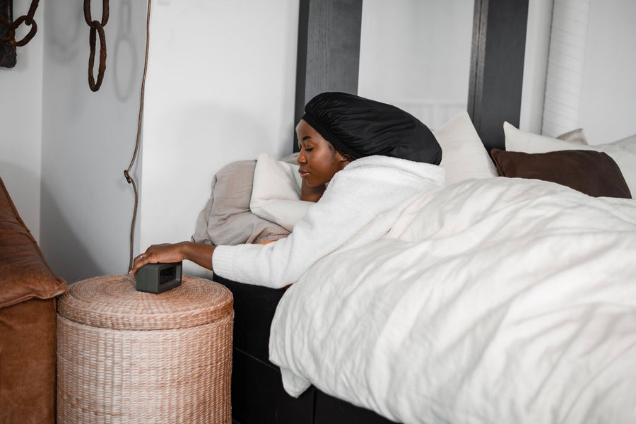Frau mit Satin-Bonnet liegt im Bett und schützt ihre Locken über Nacht