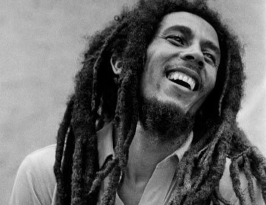 Schwarz-Weiß-Portrait eines lachenden Bob Marleys mit langen Dreadlocks